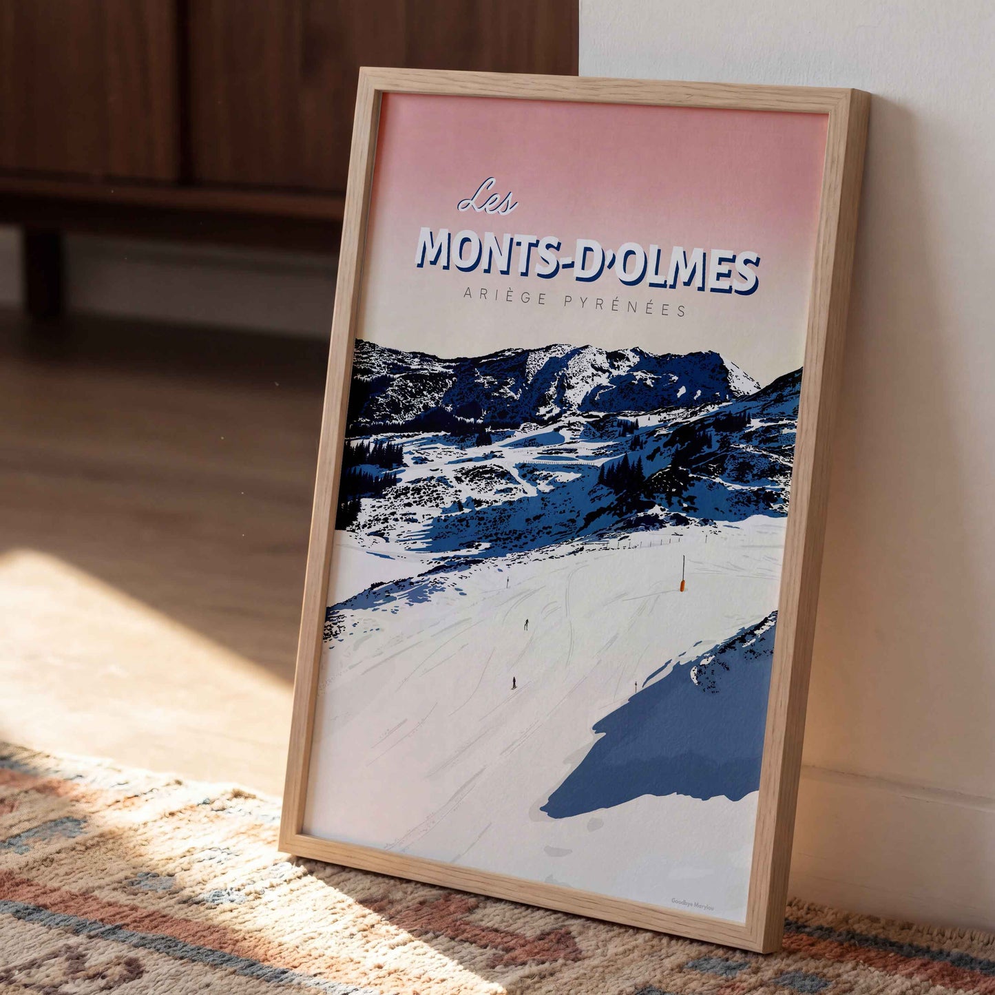 Gros plan d’une affiche Goodbye Marylou des Monts-d’Olmes encadrée, posée verticalement sur un tapis à motifs dans un intérieur ensoleillé.