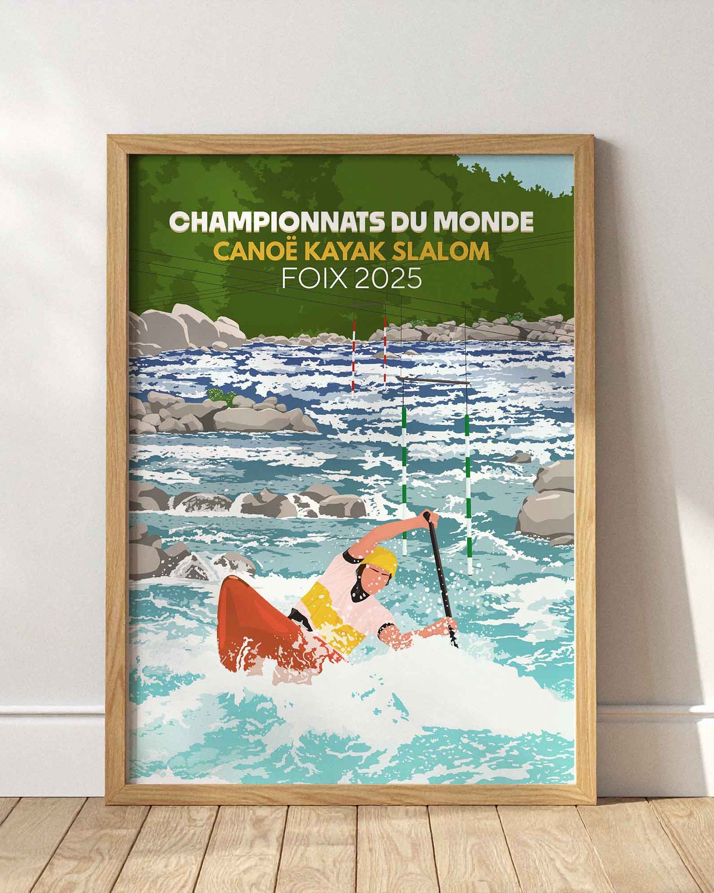 Affiche des Championnats du Monde de Canoë-Kayak Slalom Foix 2025 dans un cadre en bois clair, posée au sol contre un mur blanc épuré.