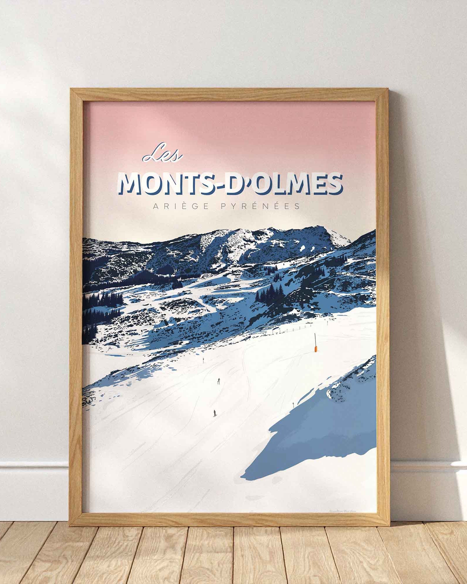 Affiche de la station des Monts-d’Olmes encadrée en bois clair, posée au sol contre un mur blanc épuré avec des ombres portées de fenêtres.
