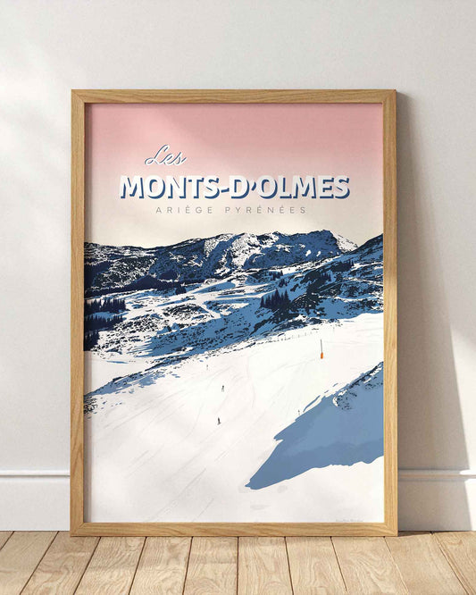 Affiche de la station des Monts-d’Olmes encadrée en bois clair, posée au sol contre un mur blanc épuré avec des ombres portées de fenêtres.