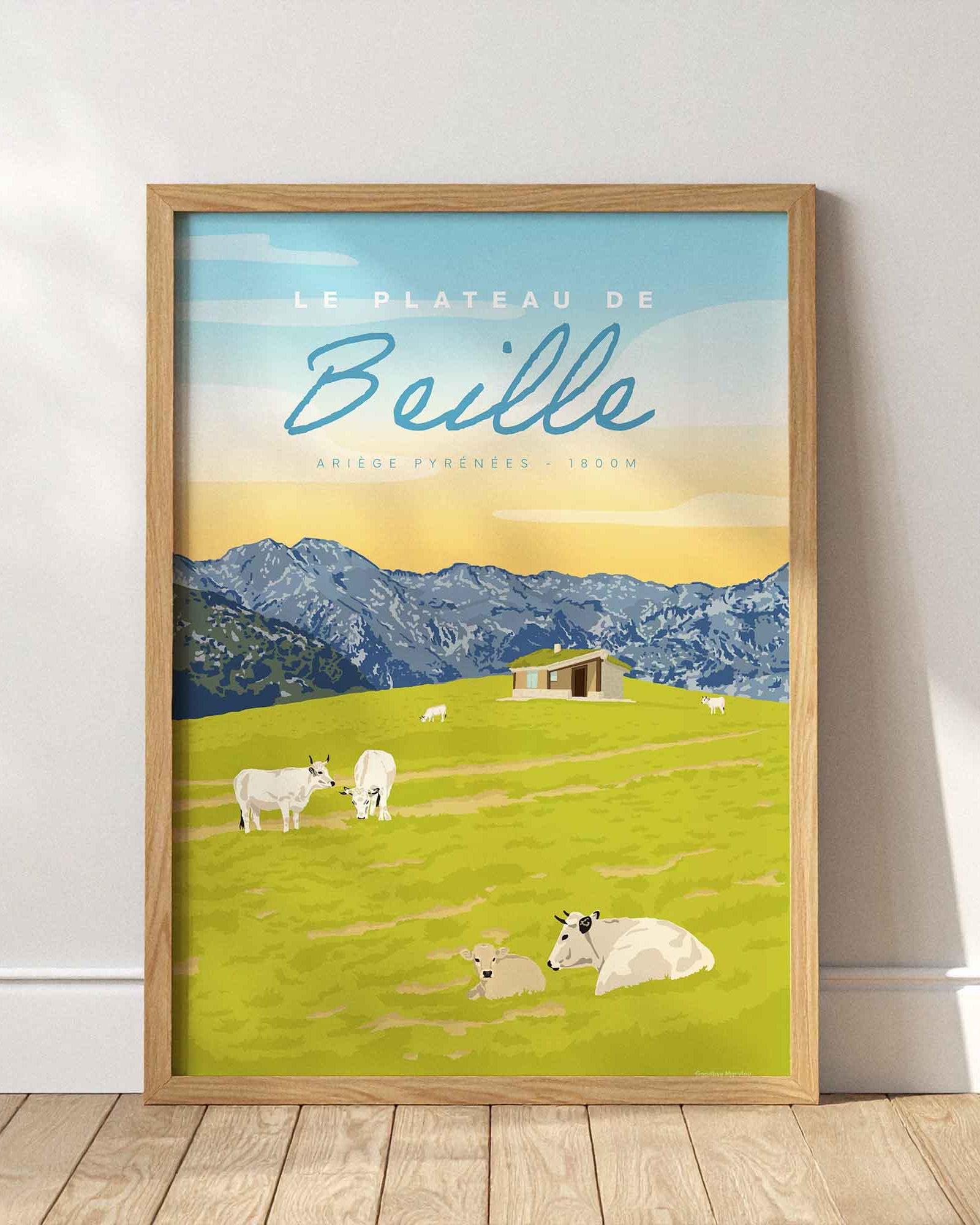 Affiche du Plateau de Beille en été encadrée en bois clair, posée au sol contre un mur blanc épuré avec des jeux d'ombres de fenêtres.