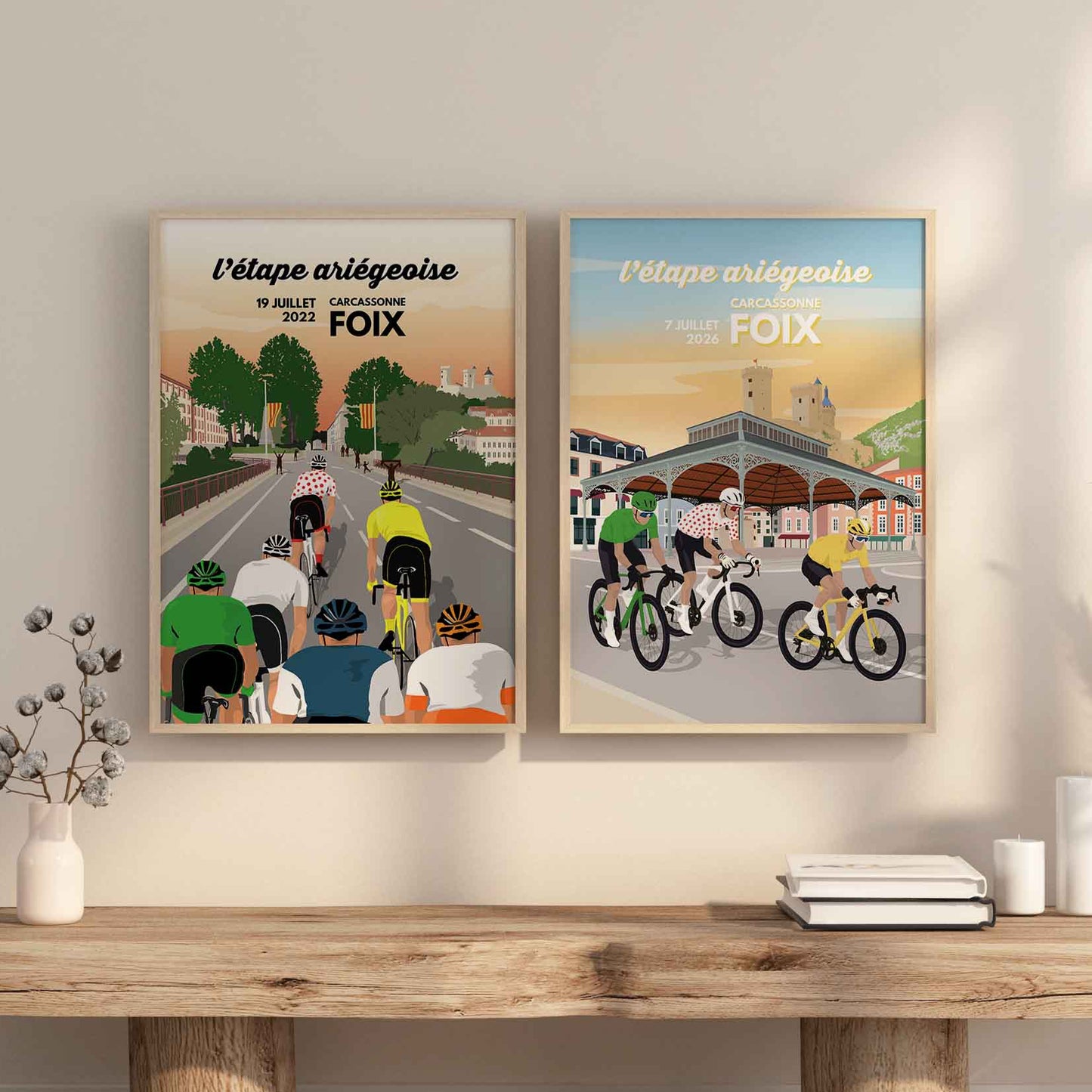 Décoration murale cyclisme Pyrénées : les deux affiches Foix 2022 et 2026 posées sur une console en bois, idée cadeau pour fan de vélo.