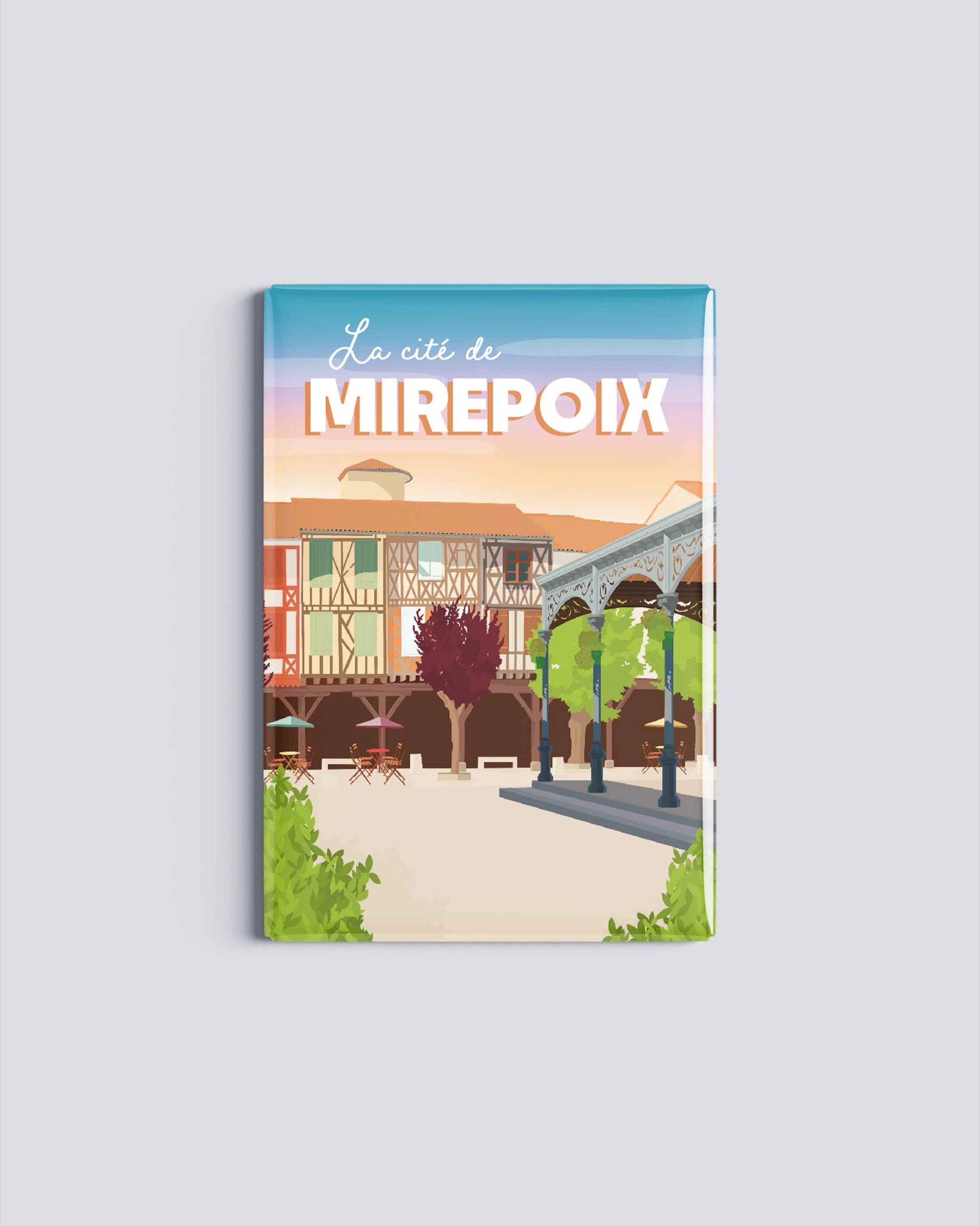 Magnet rectangulaire avec une illustration de la cité médiévale de Mirepoix en Ariège montrant les maisons à colombages et les arcades sous un ciel de fin de journée.