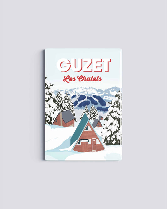 Magnet rectangulaire avec une illustration de la station de Guzet montrant les chalets enneigés et les sapins sous la neige en Ariège.