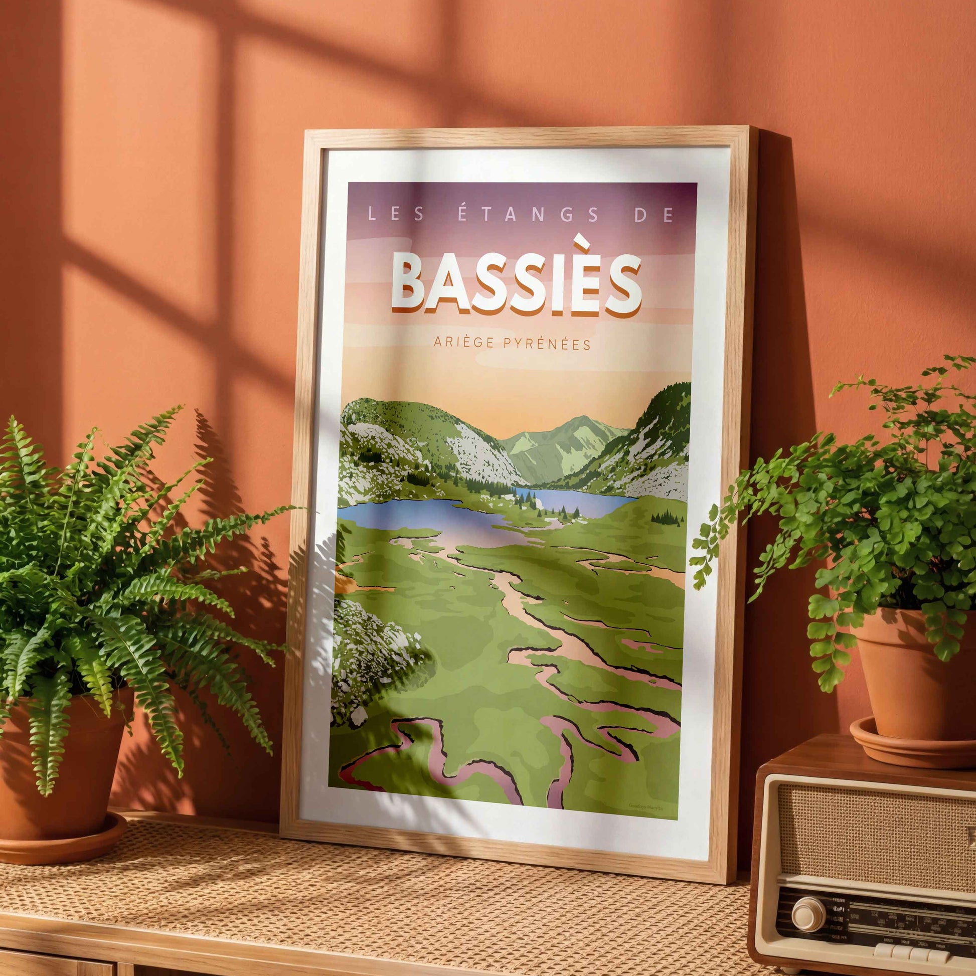 Affiche Bassiès encadrée, posée sur une étagère en bois devant un mur de couleur terracotta avec des plantes vertes.