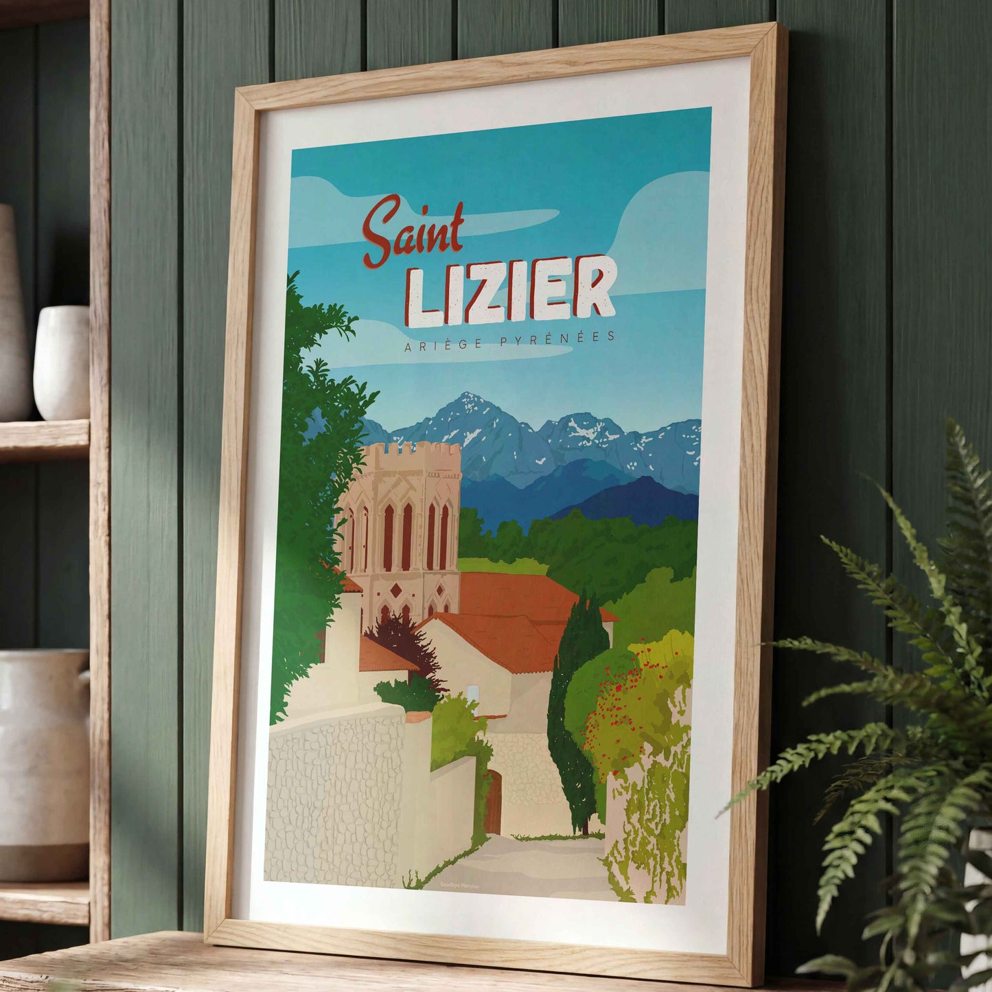 Affiche décorative de Saint-Lizier dans un cadre en bois, posée sur un meuble devant un mur de couleur vert forêt avec des plantes d'intérieur