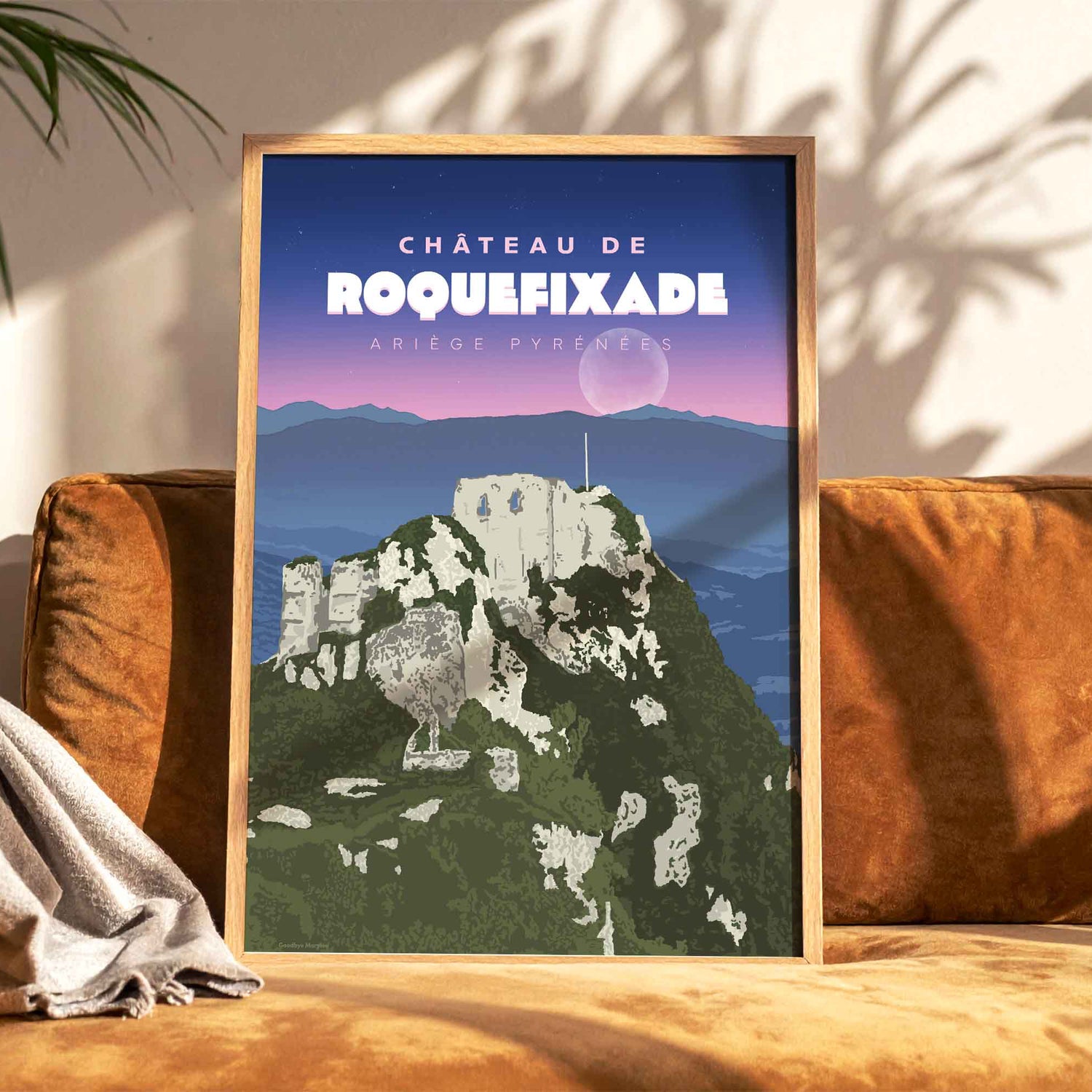 Affiche de l'Ariège sous la lune posée sur un canapé en velours terracotta, créant une ambiance chaleureuse. 