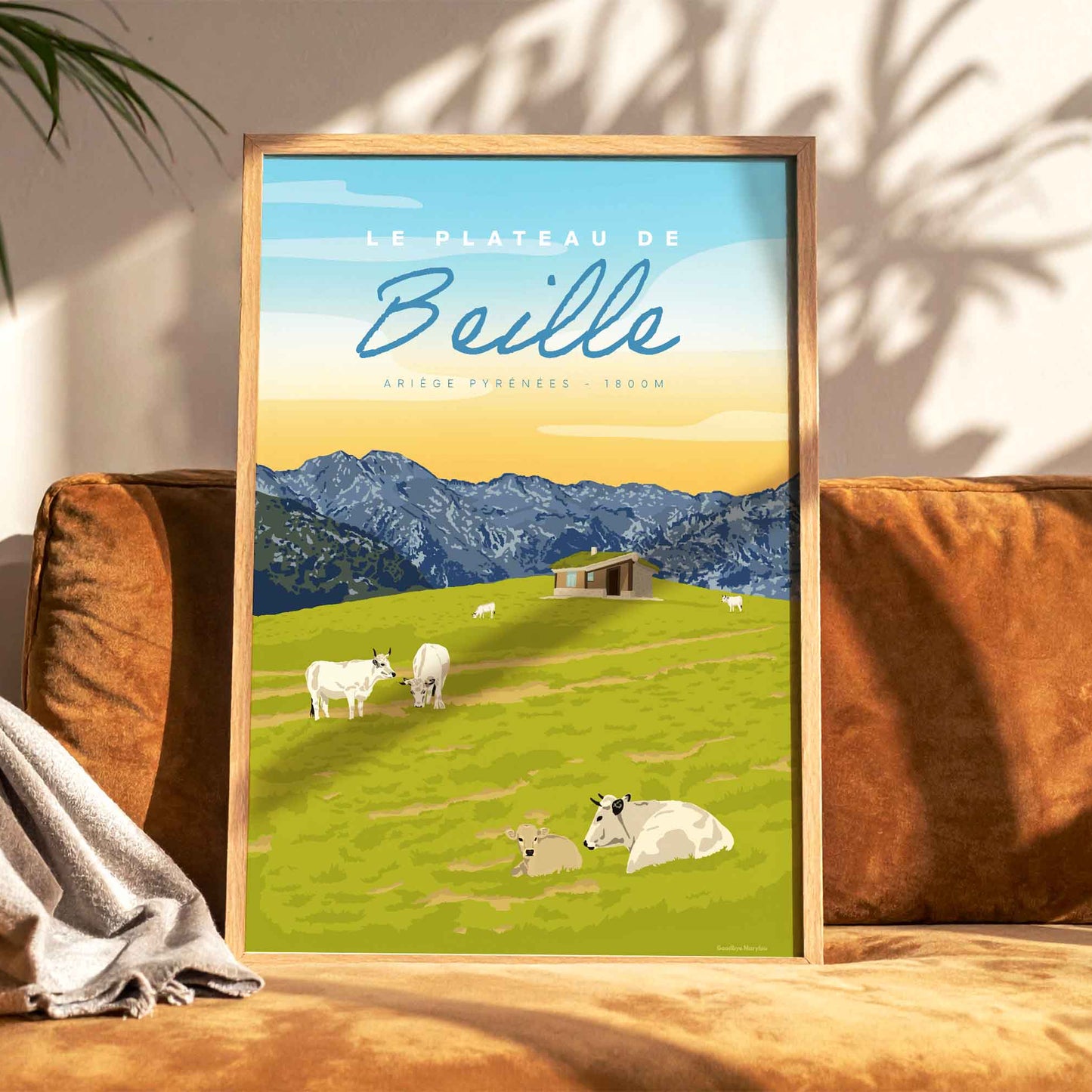 Affiche décorative du Plateau de Beille en été posée sur un canapé en velours terracotta, créant une ambiance de salon chaleureuse et naturelle.
