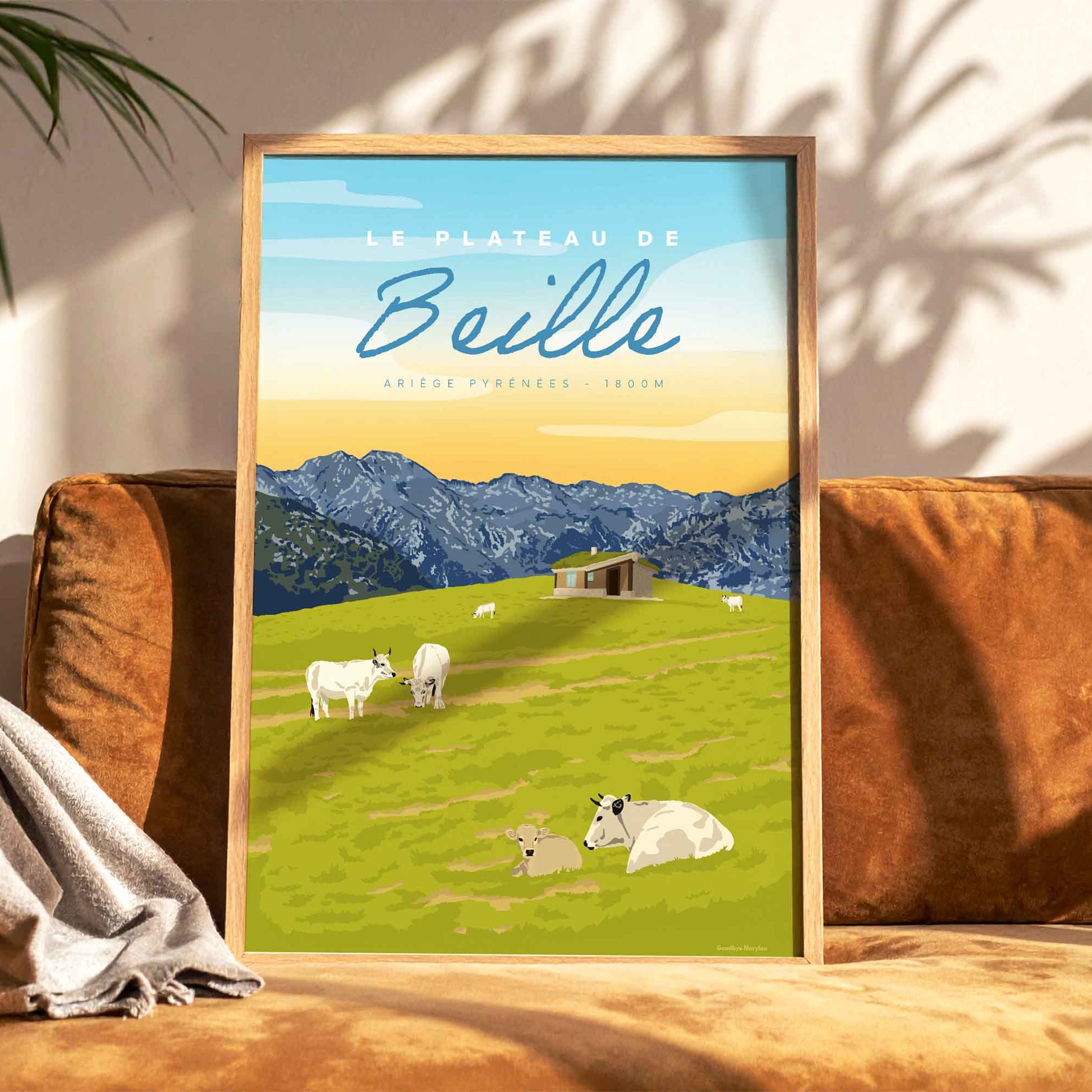 Affiche décorative du Plateau de Beille en été posée sur un canapé en velours terracotta, créant une ambiance de salon chaleureuse et naturelle.

