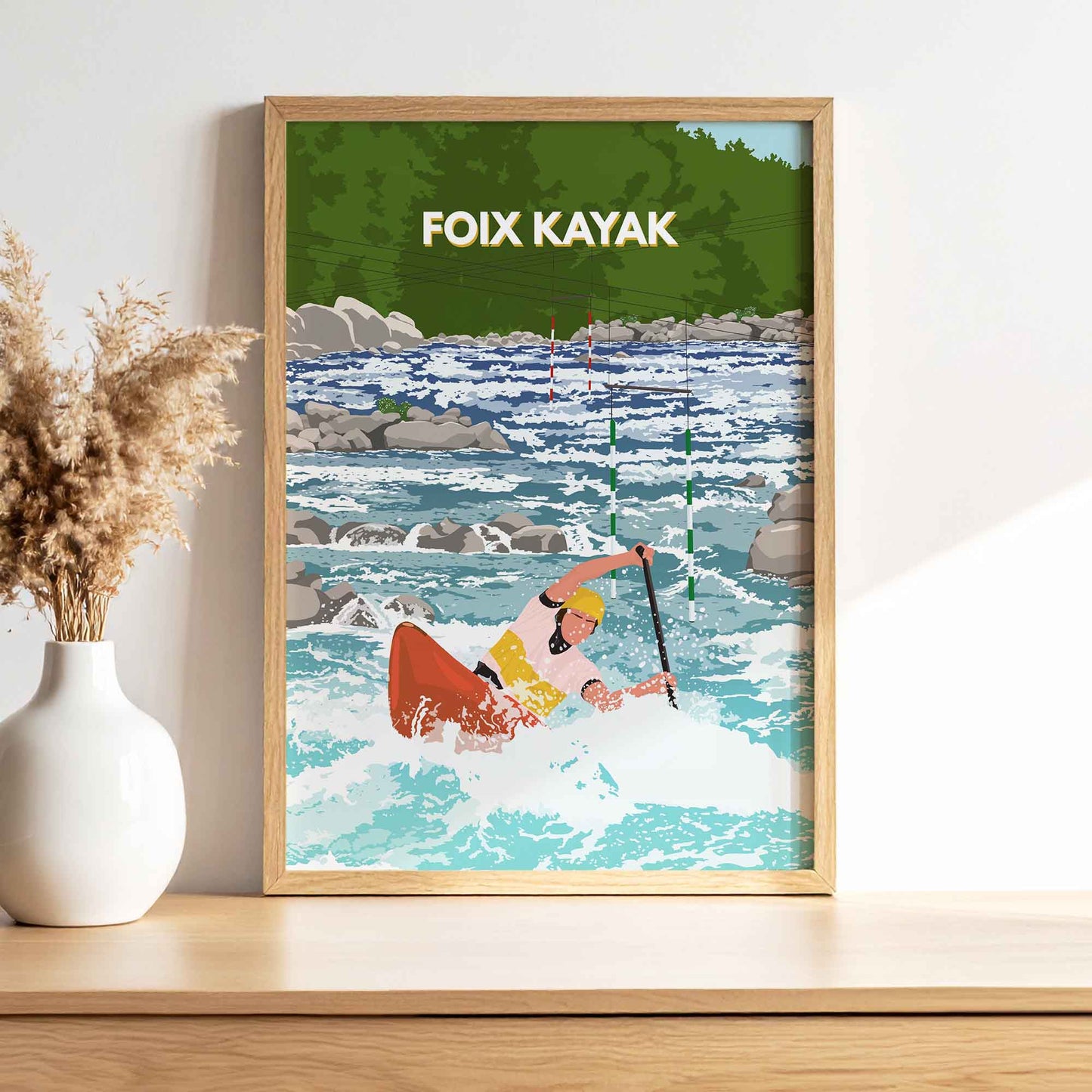 Affiche décorative de kayak à Foix exposée dans un cadre en bois sur une étagère, accompagnée d'un vase blanc et de fleurs séchées.
